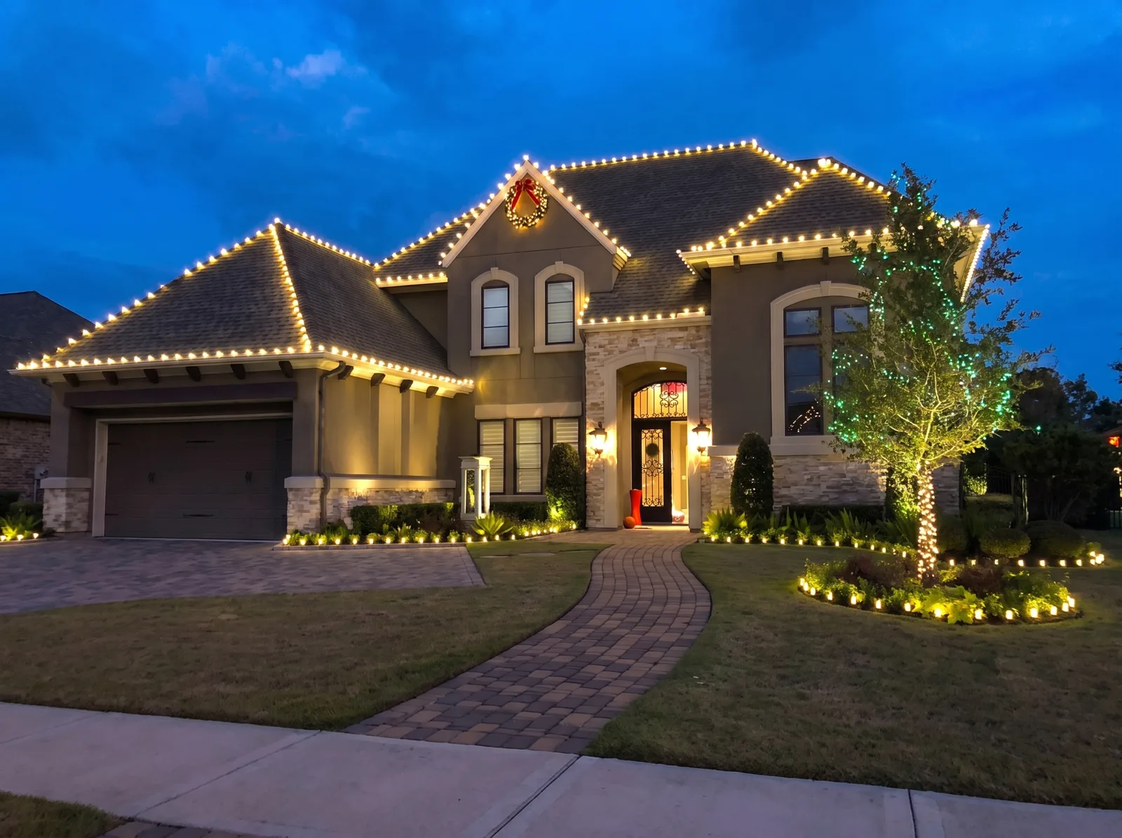 A Houston-area home at dusk with a full warm-white Christmas lighting display by LUX
